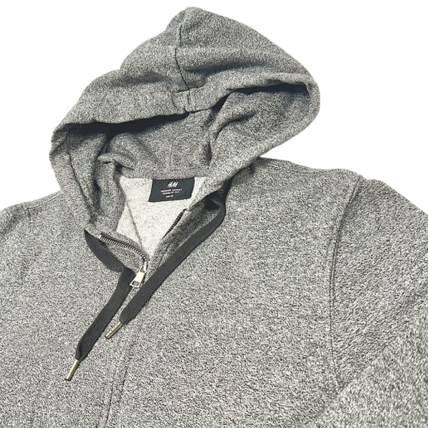 Sudadera con cremallera gris de H&M para hombre, diseño casual con capucha y cierre frontal.