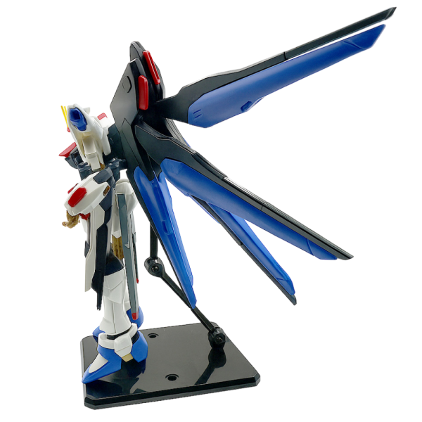 Gunpla Strike Freedom figure on display stand, showcasing detailed wings and armor from side view.