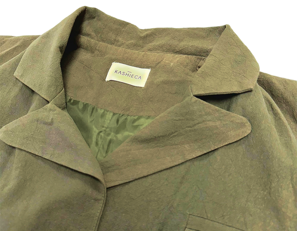 Chaleco largo mujer Kashieca en verde oliva, detalle de cuello y etiqueta, ideal para looks elegantes.