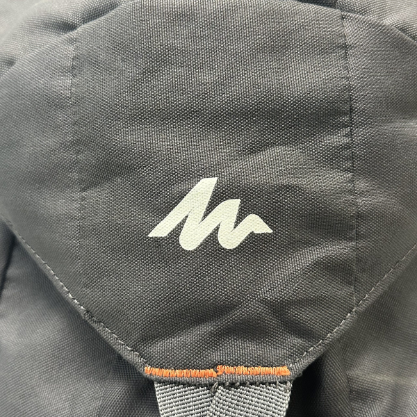 Close-up of Quechua Arpenaz, best rucksack for hiking, featuring durable gray fabric and logo on the backpack.