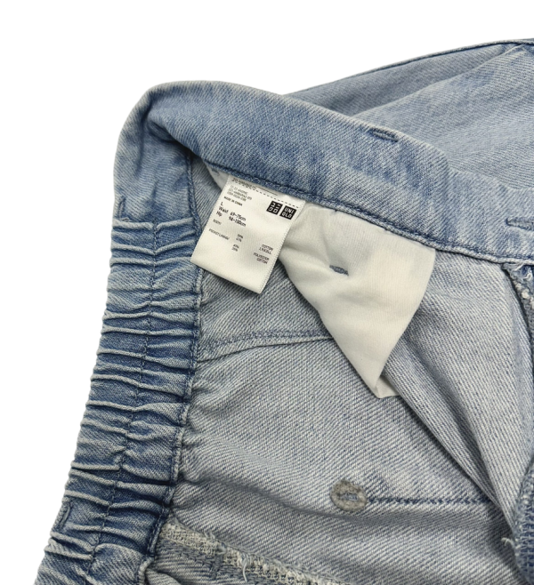 Close-up of waistband and tag detail on Uniqlo women's wide-leg jeans in light blue denim.