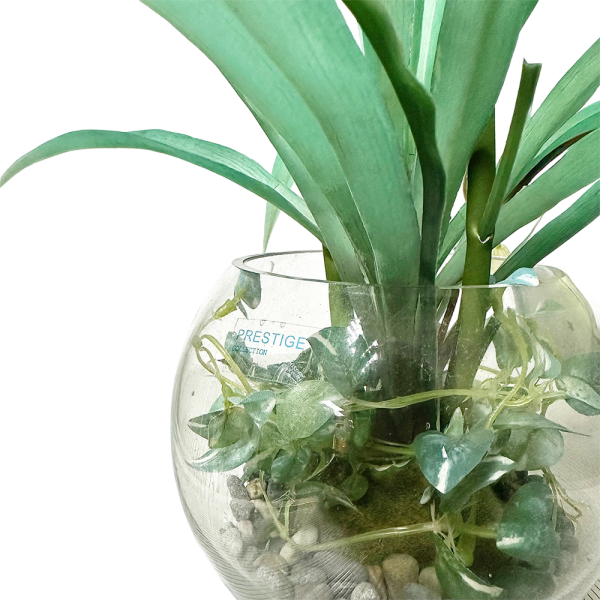 Arreglo de topiaria con plantas artificiales en maceta de vidrio decorativa, ideal para interiores.
