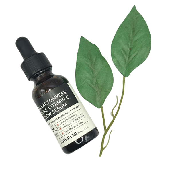 Sérum para la cara Some By Mi Vitamina C junto a hojas verdes, ideal para cuidado facial e iluminación.