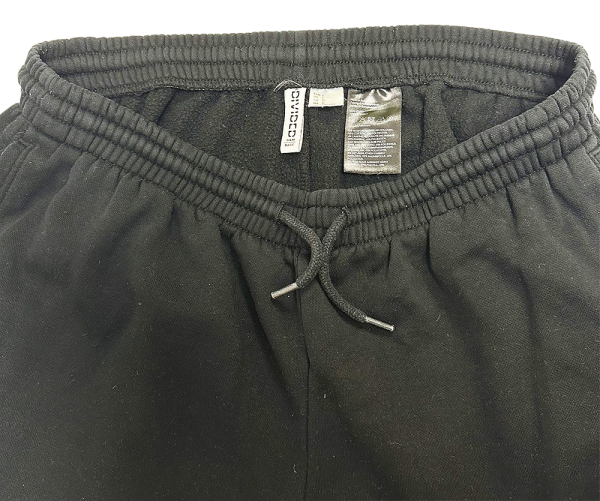 Close-up of black H&M women's sweatpants waistband with drawstring and inner tags visible.