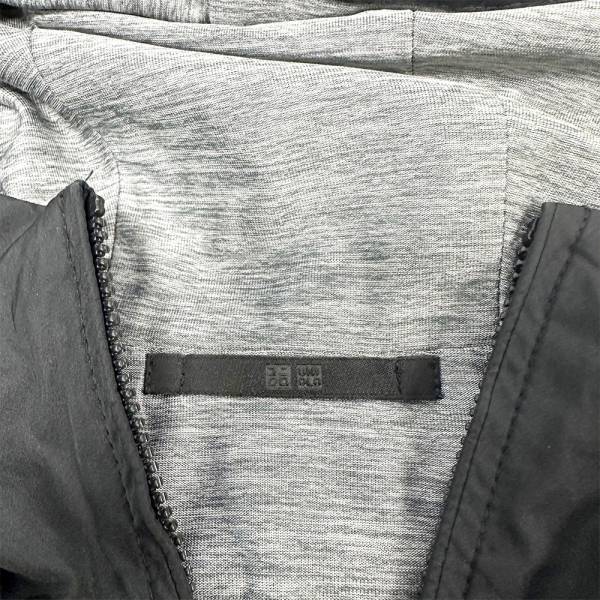 Detalle del interior de una chaqueta reversible Uniqlo, mostrando tela gris y etiqueta en el cuello.